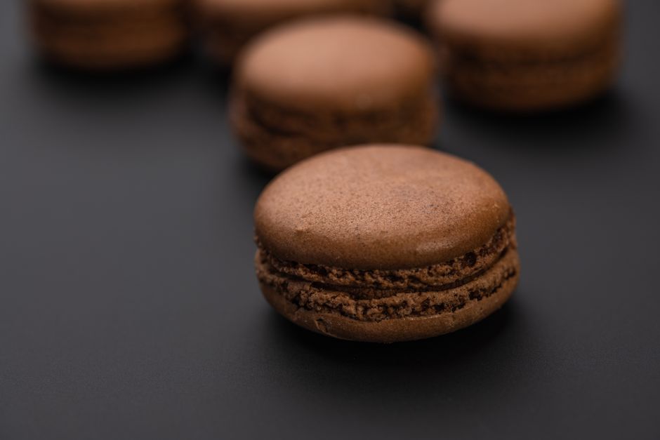 Macarons au chocolat sur fond noir, mettant en avant leur texture lisse et brillante.