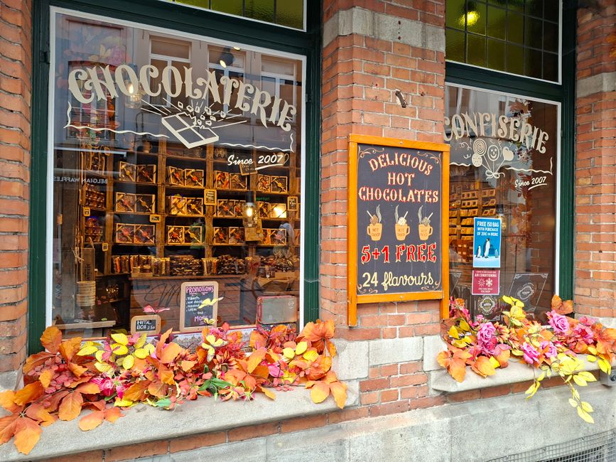 Vitrine d'une chocolaterie avec des décorations automnales et des affiches de chocolats chauds.