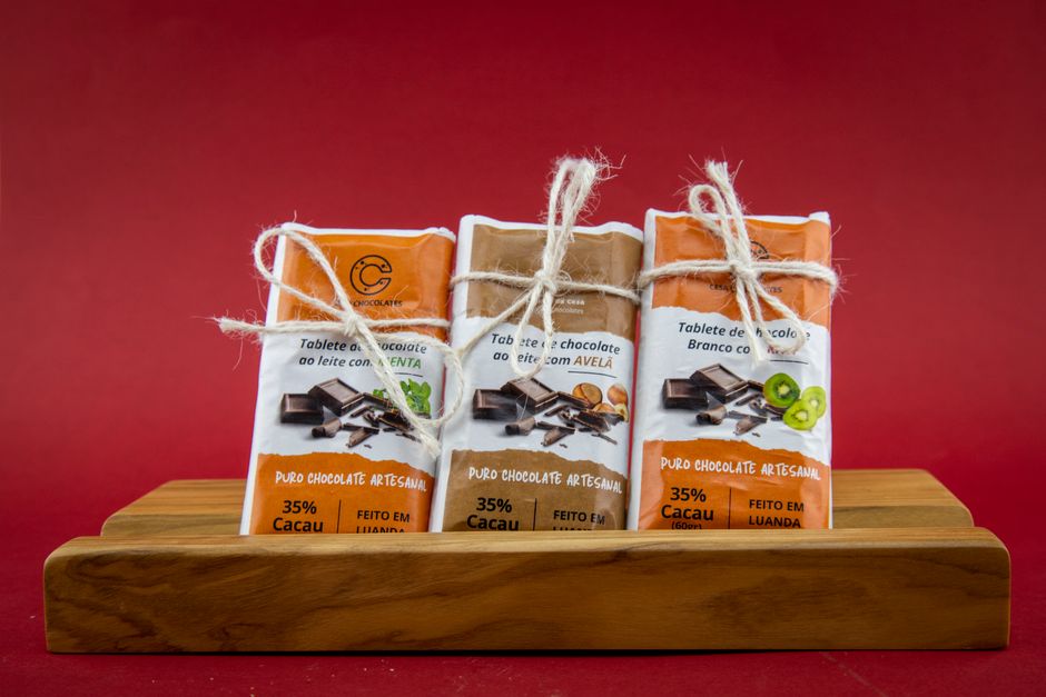 Trois tablettes de chocolat emballées sur un support en bois, avec un fond rouge, illustrant la conservation du chocolat.