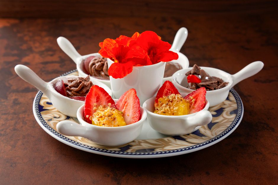 Assiette décorative avec desserts au chocolat, fraises et fleurs comestibles, illustrant un accord gourmand.