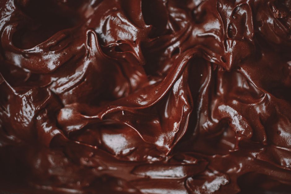 Gros plan sur une ganache au chocolat lisse et brillante, illustrant sa texture crémeuse et riche.