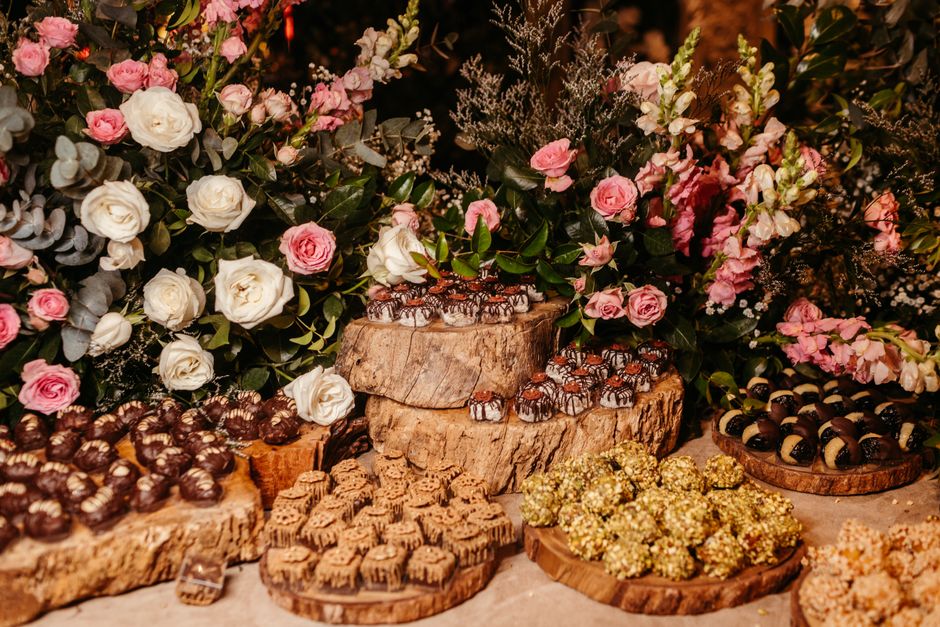 Bouquet de fleurs colorées avec des chocolats variés présentés sur des plateaux en bois.