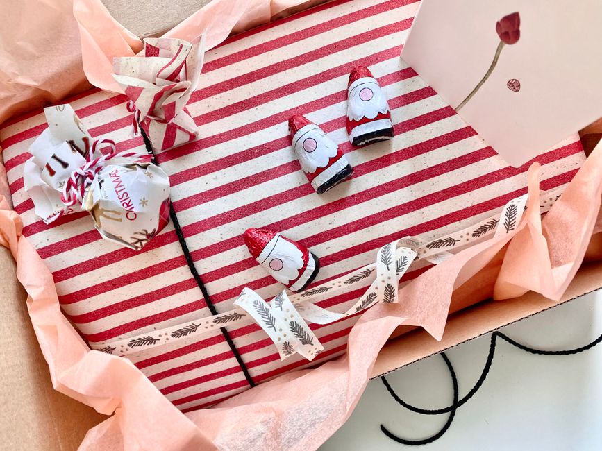 Emballage de chocolats maison avec papier rayé, rubans et décorations dans une boîte en carton.
