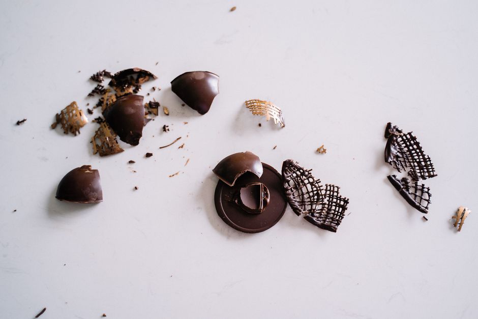 Morceaux de chocolat cassés sur une surface blanche, évoquant des confiseries élégantes.