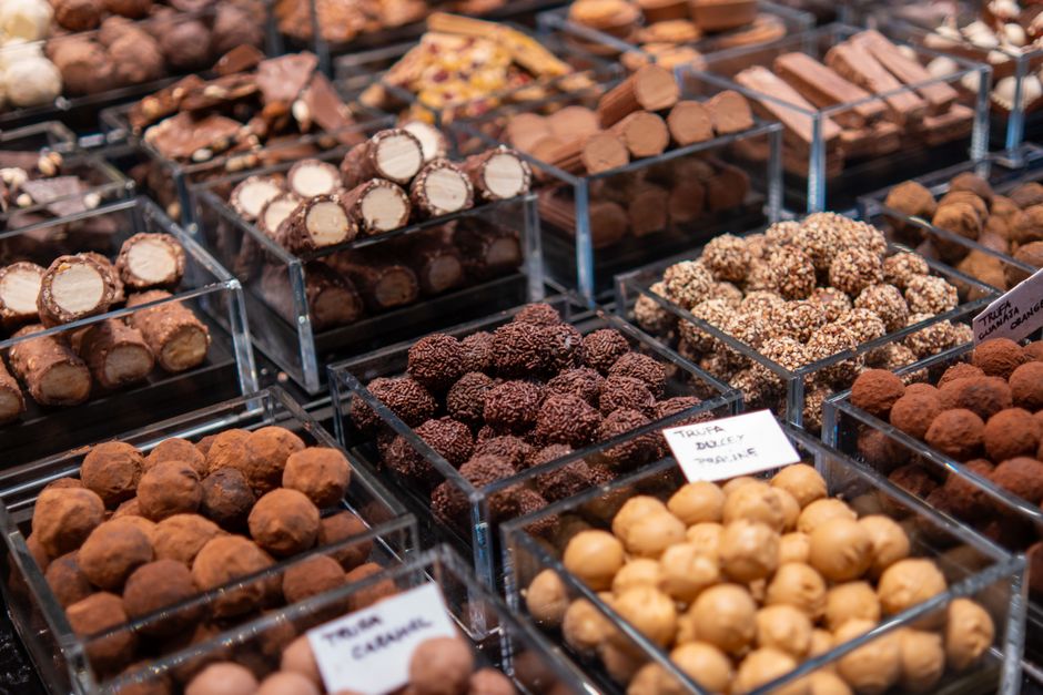 Assortiment de pralines artisanales de différentes formes et saveurs dans des bocaux transparents.