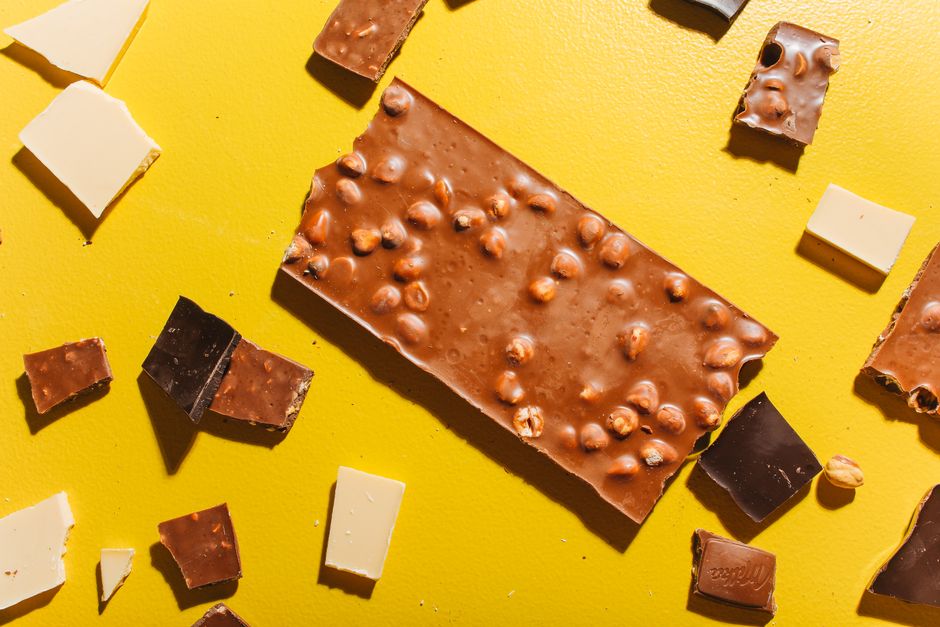 Assortiment de morceaux de chocolat et praliné sur fond jaune, illustrant des conseils de conservation.
