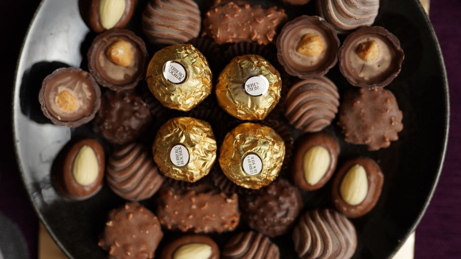 Assortiment de pralines artisanales sur un plateau, incluant des chocolats fourrés et des bonbons enrobés.