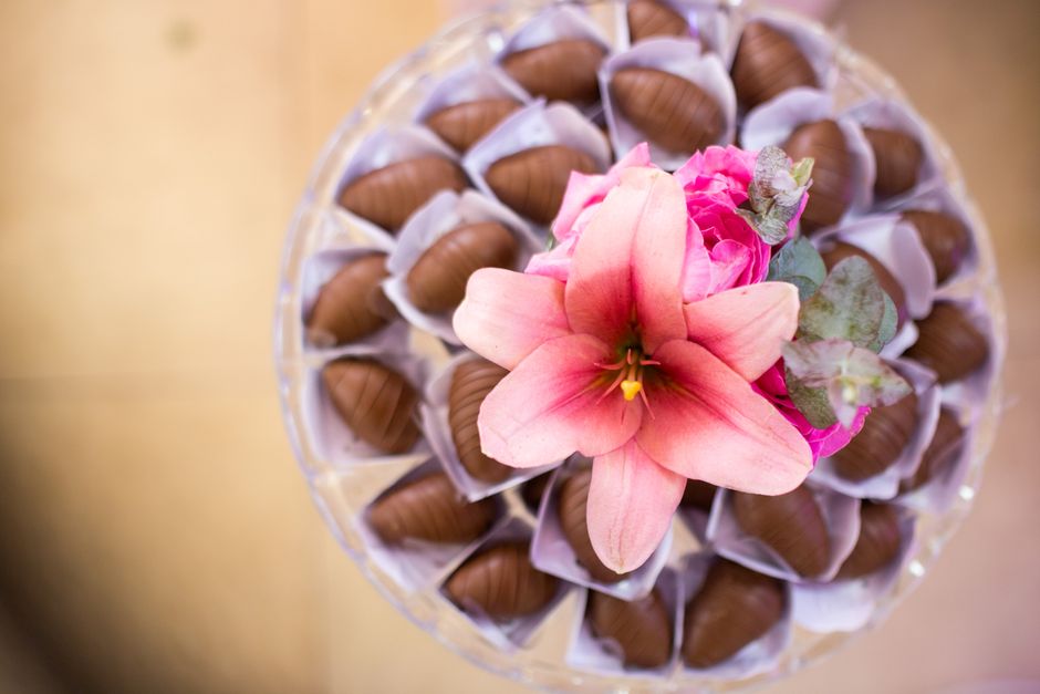Fleurs roses et chocolat enrobé disposés sur un plateau, illustrant l'accord entre saveurs et parfums.