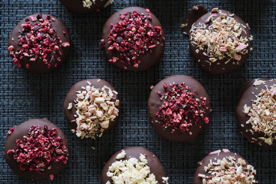 Assortiment de confiseries chocolatées avec éclats de fruits rouges et noix sur un fond texturé.