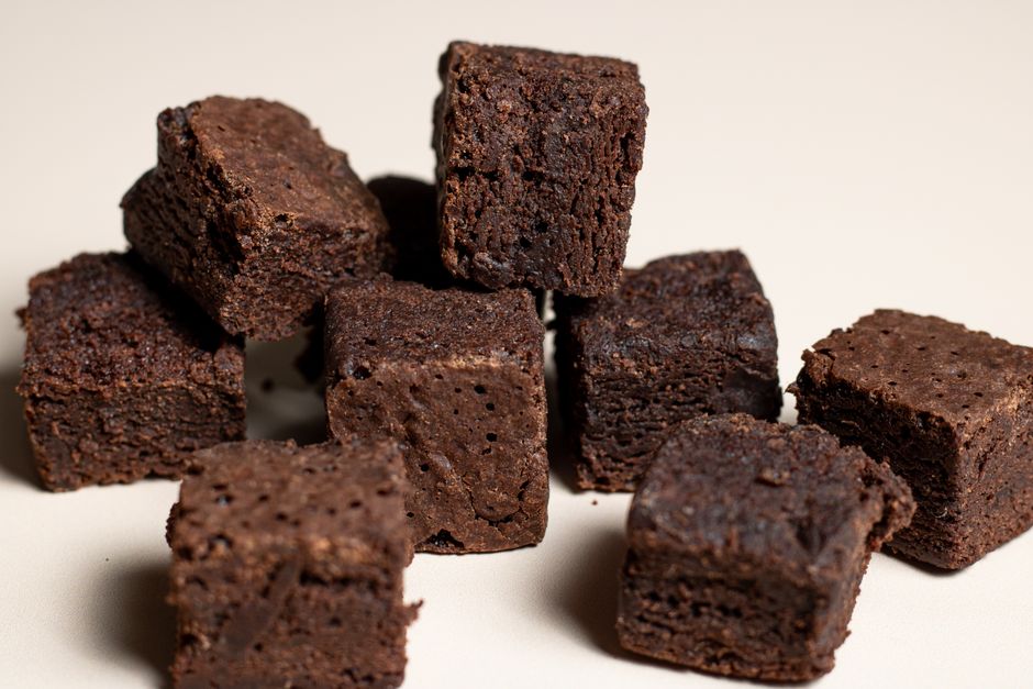 Dix cubes de brownies fondants disposés sur une surface claire, prêts à être présentés dans un coffret.
