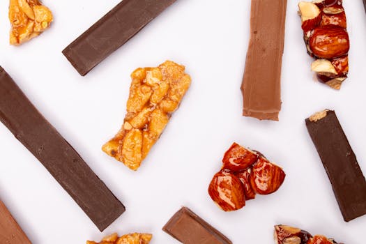 Mélange de croustillants pralinés maison avec morceaux de chocolat et fruits secs sur fond blanc.