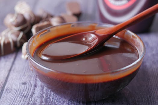 Bol de praliné maison avec une cuillère en bois, sur un fond de chocolat et de douceurs chocolatées.