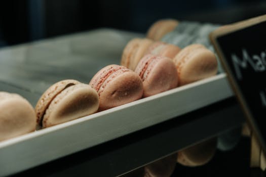 Assortiment de macarons colorés sur un plateau, mettant en valeur des nuances de rose et beige.