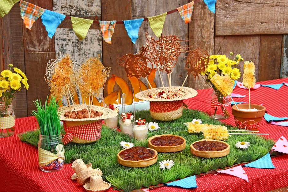 Table festive décorée avec des desserts variés, praliné noisette, fleurs et guirlandes colorées sur fond en bois.
