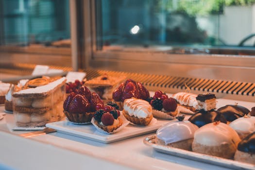 Vitrine de pâtisserie avec divers desserts colorés, incluant tartes aux fruits et éclairs.